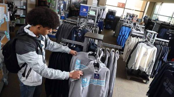 student looking at sweatshirts in a rack